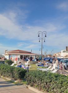a group of people sitting on benches in a parking lot at The Way of the Tower in Isola Sacra