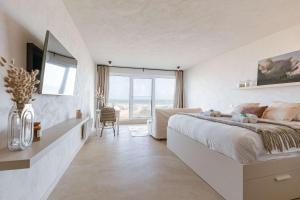 a white bedroom with a large bed and a large window at Huswell - Modern studio with magnificent seaview in Koksijde