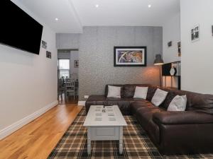 un salon avec un canapé en cuir marron et une table dans l'établissement Flat 2 23 Hyde Park Road, à Harrogate