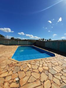 a blue swimming pool on a stone patio at Chácara in Franco da Rocha