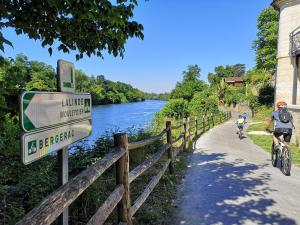 Dos personas en bicicleta por un camino junto a un río en Ele STUDIO indépendant, en Bergerac