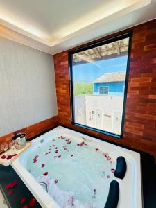 a jacuzzi tub in a room with a large window at Pousada Amaral Búzios in Búzios
