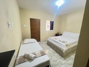 a room with two beds and a light on the ceiling at Pousada Alto do Tambá in São Francisco