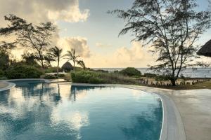 a swimming pool with the ocean in the background at The Charming Lonno Lodge Watamu in Watamu