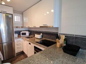 a kitchen with a stainless steel refrigerator and white cabinets at Duplex penthouse with 4 bedrooms and stunning sea views in Benalmádena