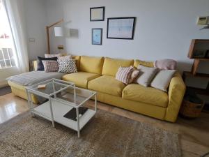 a yellow couch in a living room with a table at Duplex penthouse with 4 bedrooms and stunning sea views in Benalmádena