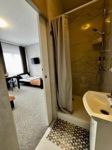 a bathroom with a shower and a sink and a bedroom at Hotelino Stare Miasto Częstochowa in Częstochowa