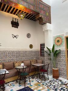 a restaurant with a couch and tables and chairs at Riad la Mentha in Fès