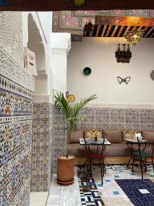 a restaurant with a couch and tables and tiles at Riad la Mentha in Fès