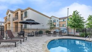 a pool with chairs and an umbrella next to a building at Lovely Apartment in Austin shopping Dining in Cedar Park