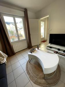 a living room with a white table and a tv at Charming house with terrace in Laval