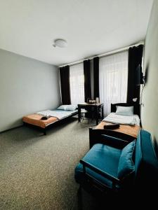 a room with two beds and a chair in it at Hotelino Stare Miasto Częstochowa in Częstochowa
