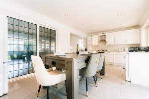 une cuisine avec une table et des chaises en bois dans l'établissement Bright & Comfy 3-BR House in Feltham and a Separate Studio - Sleeps 11!, à New Bedfont