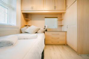 a small bedroom with two beds and a kitchen at Bright & Comfy 3-BR House in Feltham - Sleeps 7! in New Bedfont