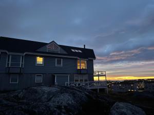 a house sitting on top of a rock at sunset at Byens bedste udsigt in Nuuk