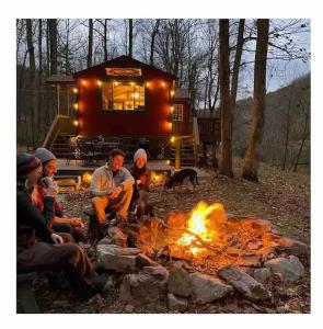 a group of people sitting around a camp fire at Cacapon Riverside Getaway in Great Cacapon