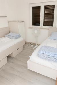 a white bedroom with two beds and a fan at Inter-nautika doo in Jezera