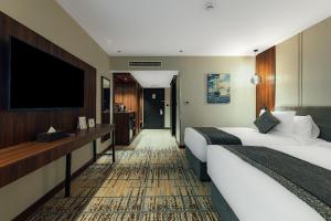 une chambre d'hôtel avec deux lits et une télévision à écran plat dans l'établissement VERTA Al Olaya Hotel, à Riyad