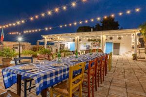a long table with chairs and lights on a patio at Masseria Dipinto di Blù in Felline