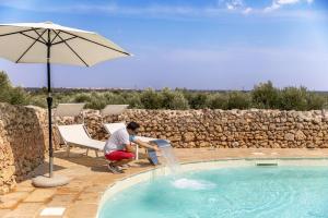 a boy sitting in a chair drinking from a fountain in a pool at Masseria Dipinto di Blù in Felline