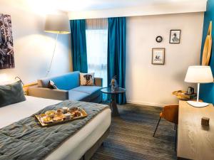 ein Hotelzimmer mit einem Bett und einer Couch in der Unterkunft Hotel Mercure Château de Fontainebleau in Fontainebleau
