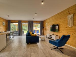a living room with two blue chairs and a tv at Dom przy lesie in Wielgie