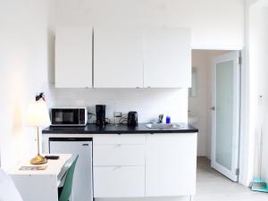 Una cocina con gabinetes blancos y un microondas. en Villas at Auxilio Mutuo 106, en San Juan