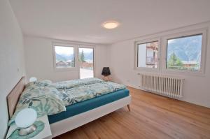 a bedroom with a bed and two windows at Bishorn, Chalet Wiedersehn in Grächen