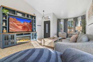 a living room with a large tv and a fireplace at Heated Pool, Hot Tub, Games & more! in Mesa