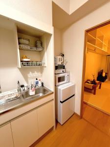 a kitchen with a sink and a microwave at Wa Shinsaka 902 7minute walk from Shinsakacho Station Maximum 4 people Separate bath and toilet Washing machine with dryer in Nagoya