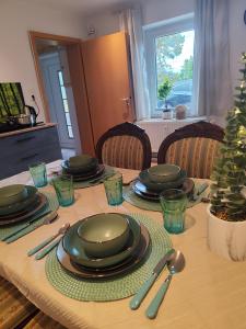 una mesa con platos verdes y utensilios. en Monteur Ferienwohnungen Auetal, en Bad Bodenteich 7 fotos más