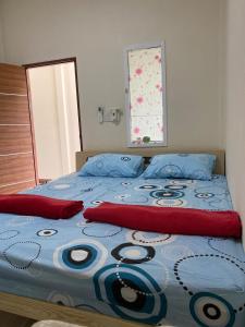 a bed with a blue comforter and red pillows at kubu home stay in Ban Ko Sawat