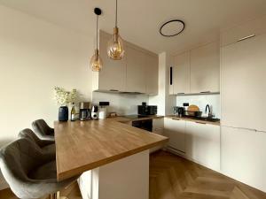 Una cocina con gabinetes blancos y una encimera de madera. en Jarzebinowa Loft III by JumpInHere, en Nowy Dwór Mazowiecki 5 fotos más