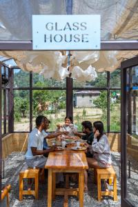 een groep mensen die aan een tafel in een glazen huis zitten bij The Winter Courtyard by AVVAs Stays in Bir