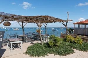a patio with a table and chairs and the ocean at Le Cabanon du Marché in Audenge