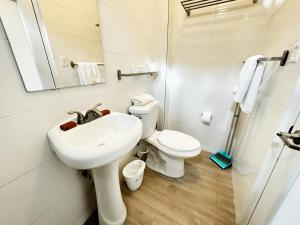 a white bathroom with a sink and a toilet at Villas at Auxilio Mutuo 103 in San Juan +14 photos