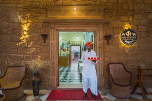 a man standing in a room with a tray of food at Wild Heritage Desert Camp in Jaisalmer