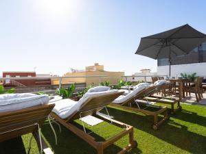 a row of lounge chairs and an umbrella on a roof at Live Güimar Las Pirámides in Güimar