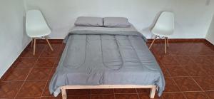 a bed sitting in a room with two chairs at Apart Sierras Chicas in Río Ceballos