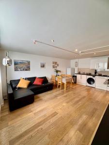 a living room with a black couch and a kitchen at Modern Apartment overlooking Andover High Street in Andover