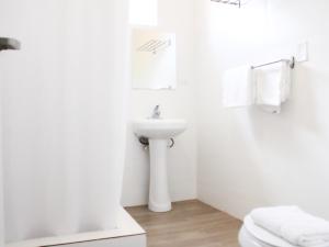 a white bathroom with a sink and a toilet at Villas at Auxilio Mutuo 102 in San Juan +6 photos