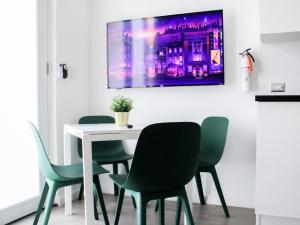 a dining room with a white table and green chairs at Villas at Auxilio Mutuo 102 in San Juan