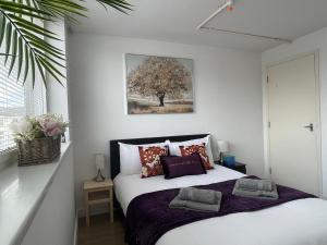 a bedroom with a bed with pillows and a tree at Modern Apartment overlooking Andover High Street in Andover