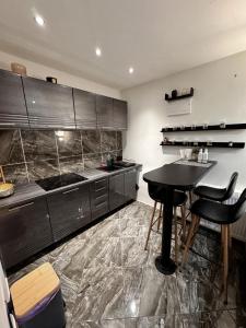 a kitchen with black cabinets and a table and chairs at La Monique - Luxury Nautical Apartment in Stará Turá