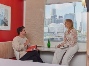 a man and a woman sitting at a table with a laptop at ibis Sydney Darling Harbour in Sydney +55 photos