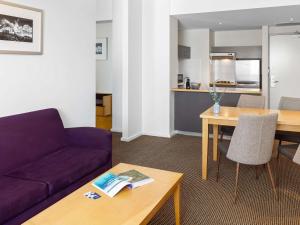 a living room with a purple couch and a table at Novotel Perth Langley in Perth