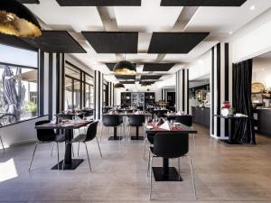 ジュエ・レ・トゥールにあるMercure Tours Sudのテーブルと椅子と窓のあるレストラン