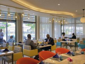 a group of people sitting at tables in a restaurant at Novotel Cotonou Orisha in Cotonou