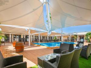 a large white umbrella over a patio with a swimming pool at Ibis Styles Karratha in Karratha