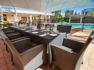 a long table with chairs and wine glasses at Ibis Styles Karratha in Karratha